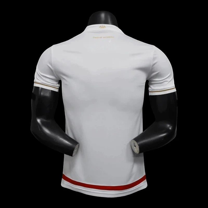 Maillot de football AS Monaco blanc et rouge pour homme, avec détails dorés sur les manches et le col. Logo de l'équipe sur la poitrine.