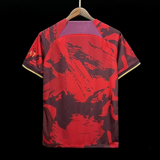 Maillot de football Paris Saint-Germain édition spéciale rouge et bordeaux avec motifs abstraits et détails dorés. Tissu respirant.