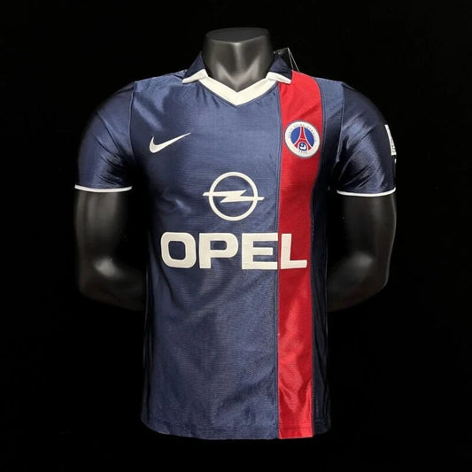 Maillot de football vintage Paris Saint-Germain bleu marine avec bande rouge, logo PSG et sponsor Opel. Finitions blanches.