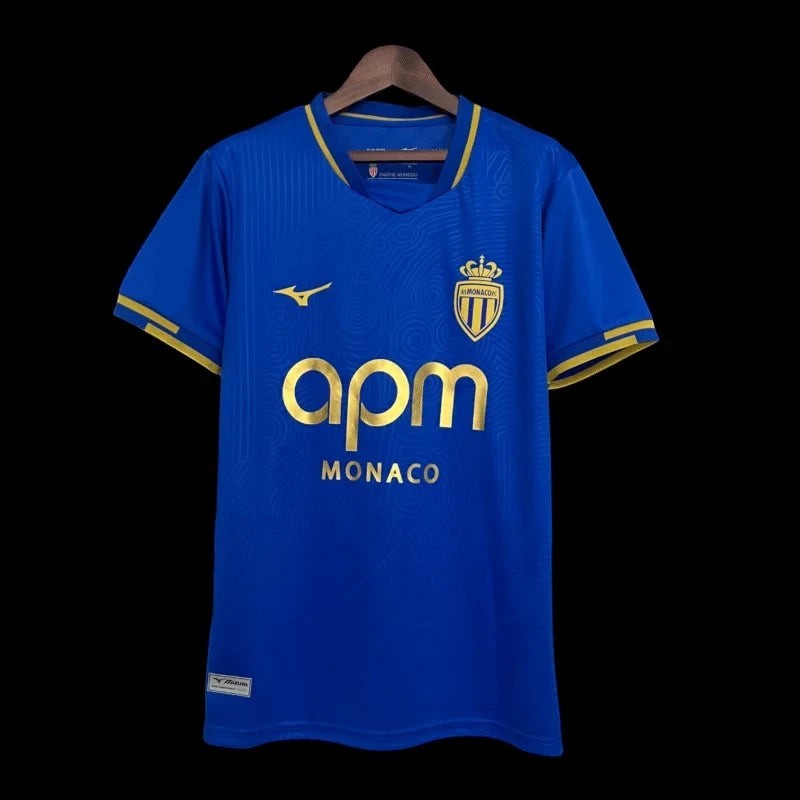 Maillot de football bleu vif pour homme AS Monaco avec détails dorés, tissu technique respirant, col polo, manches courtes, logo de l'équipe.