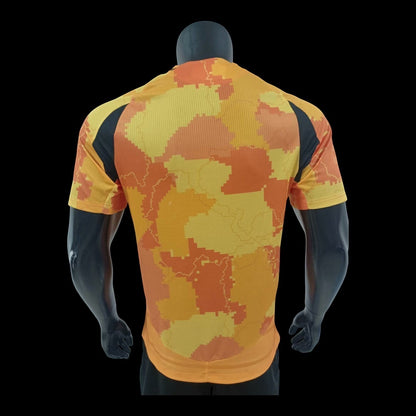 Maillot de football Paris FC Bahrain Victorious homme, motif camouflage numérique orange et jaune, panneaux latéraux noirs, tissu respirant.
