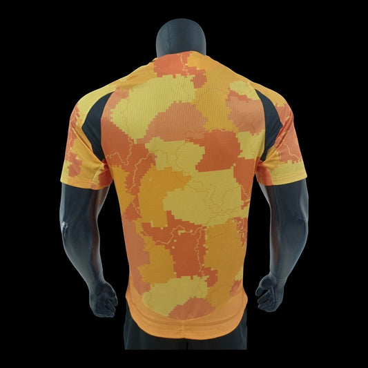 Maillot de football Paris FC Bahrain Victorious homme, motif camouflage numérique orange et jaune, panneaux latéraux noirs, tissu respirant.
