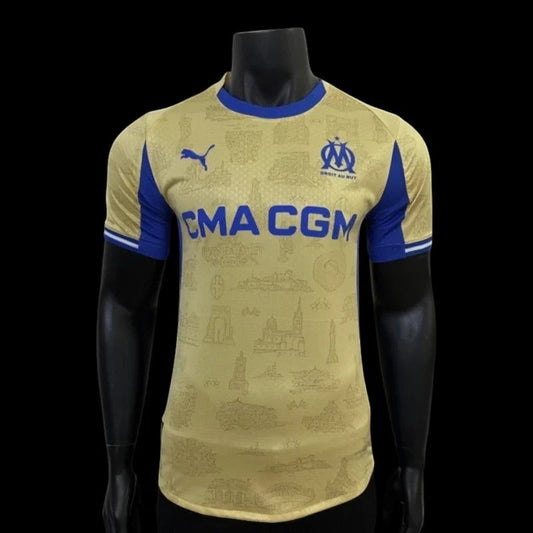 Maillot de football Olympique de Marseille domicile doré avec détails bleus, sponsor CMA CGM, logo Puma et blason OM.
