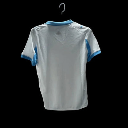 Maillot de football Olympique de Marseille blanc pour homme, col et manches bleu ciel, logo Puma et OM sur la poitrine.