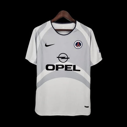 Maillot de football vintage Paris Saint-Germain gris clair avec logo Opel et touches bleues. Tissu léger et respirant.