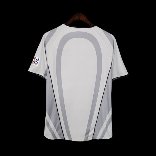Maillot de football vintage Paris Saint-Germain gris clair avec détails bleu marine et gris foncé. Logo PSG sur la poitrine.